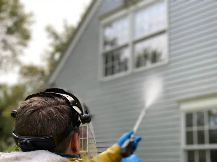 A person pressure washing house siding